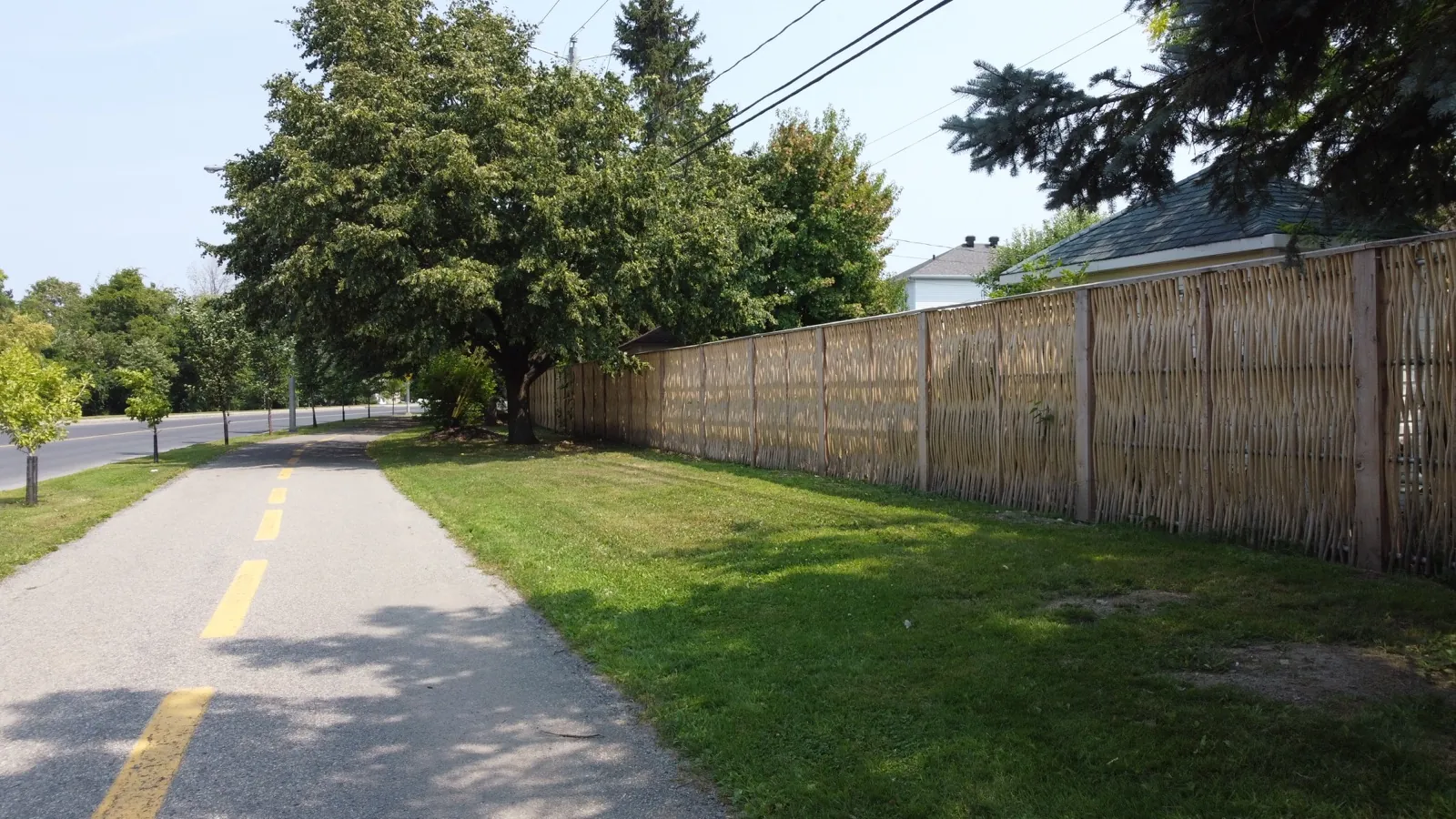 Woven willow fences between homes and a bike path in Saint-Constant, Quebec