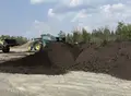 Piles de matières résiduelles fertilisantes et chargeuse sur un site de valorisation