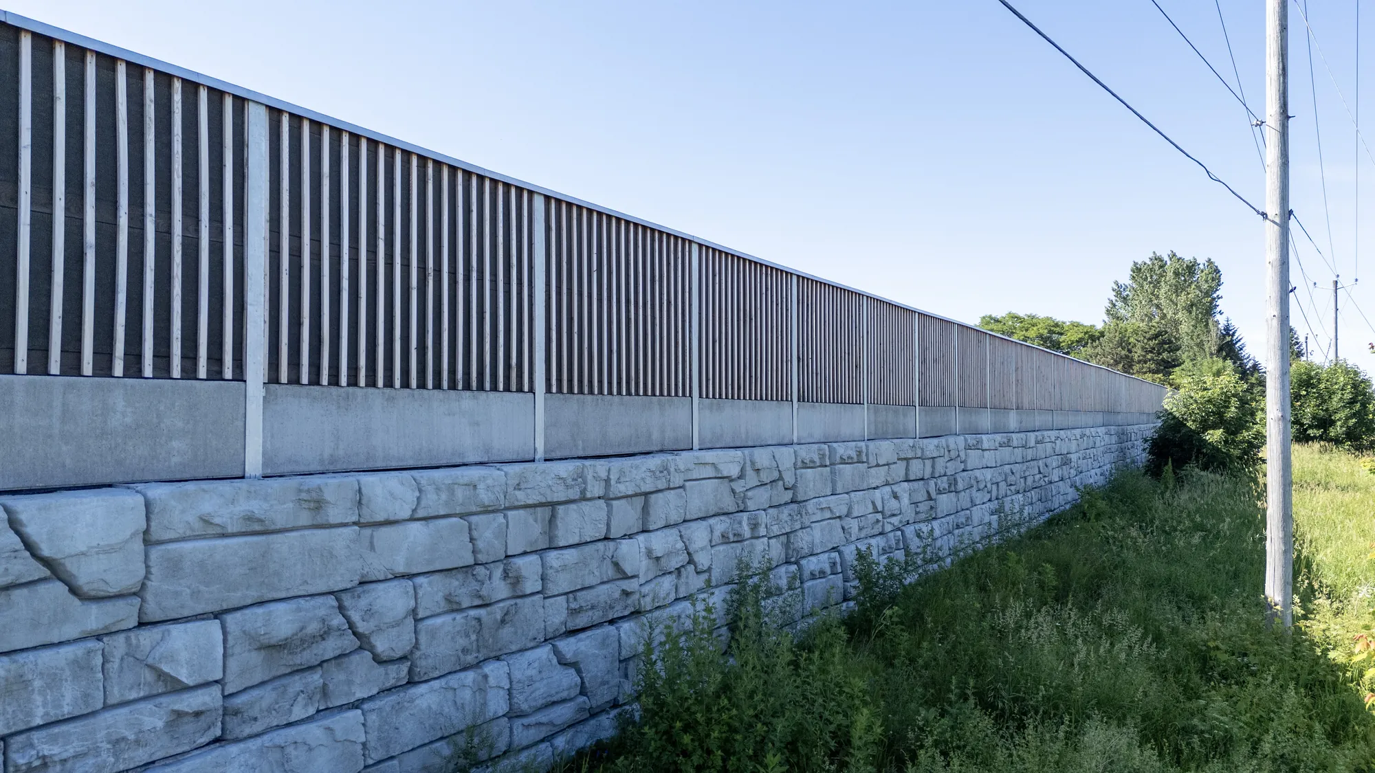 Mur antibruit HF1 en mélèze sur base de pierre à Boucherville au Québec