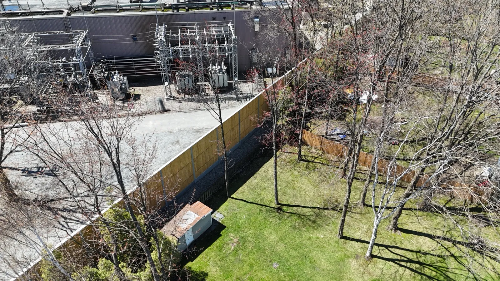 HF1 larch-wood noise barrier panels along an industrial site, drone view, Quebec