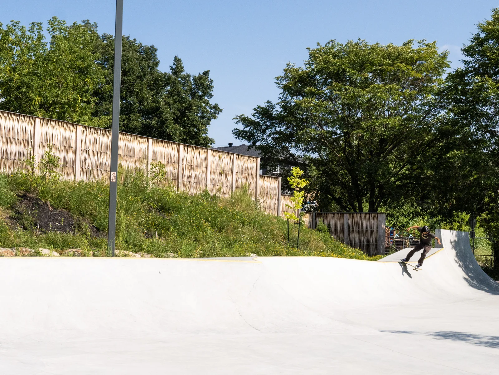 Pilebyg® willow-wood noise barrier behind a skatepark ramp, Quebec