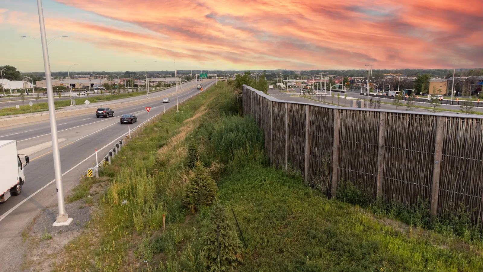 Pilebyg® willow-wood noise barrier at sunset along a highway in Quebec